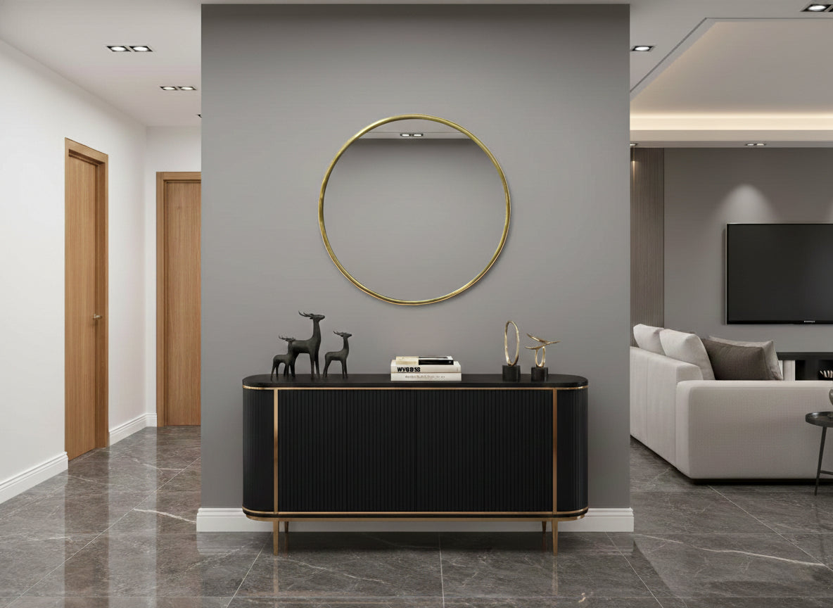 Round brass wall mirror above a black and gold console table.