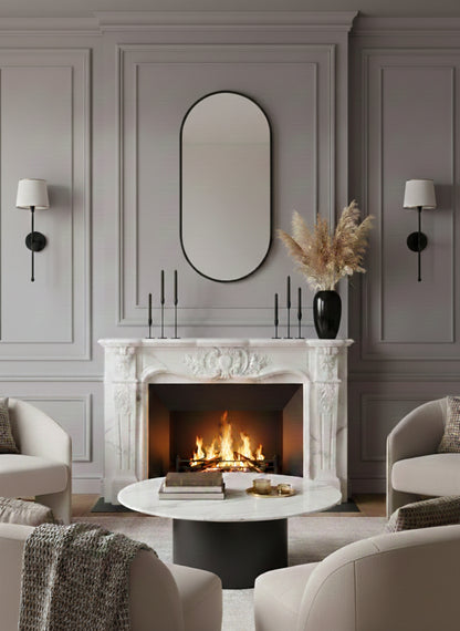 Black oval mirror above marble fireplace.