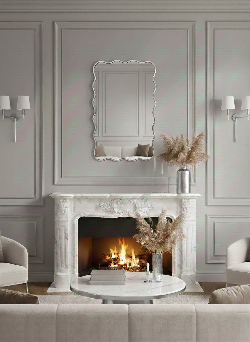 Wavy silver brass mirror above marble fireplace mantel.