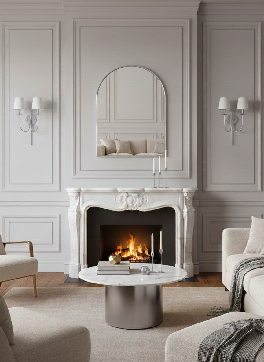 Silver arch mirror above classic white marble fireplace mantel.