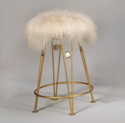 Gold bar stool with a fluffy white cushion on a gray background