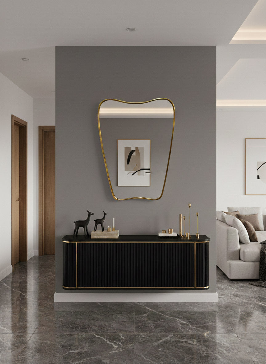 Italian curved brass mirror above black console in modern entryway