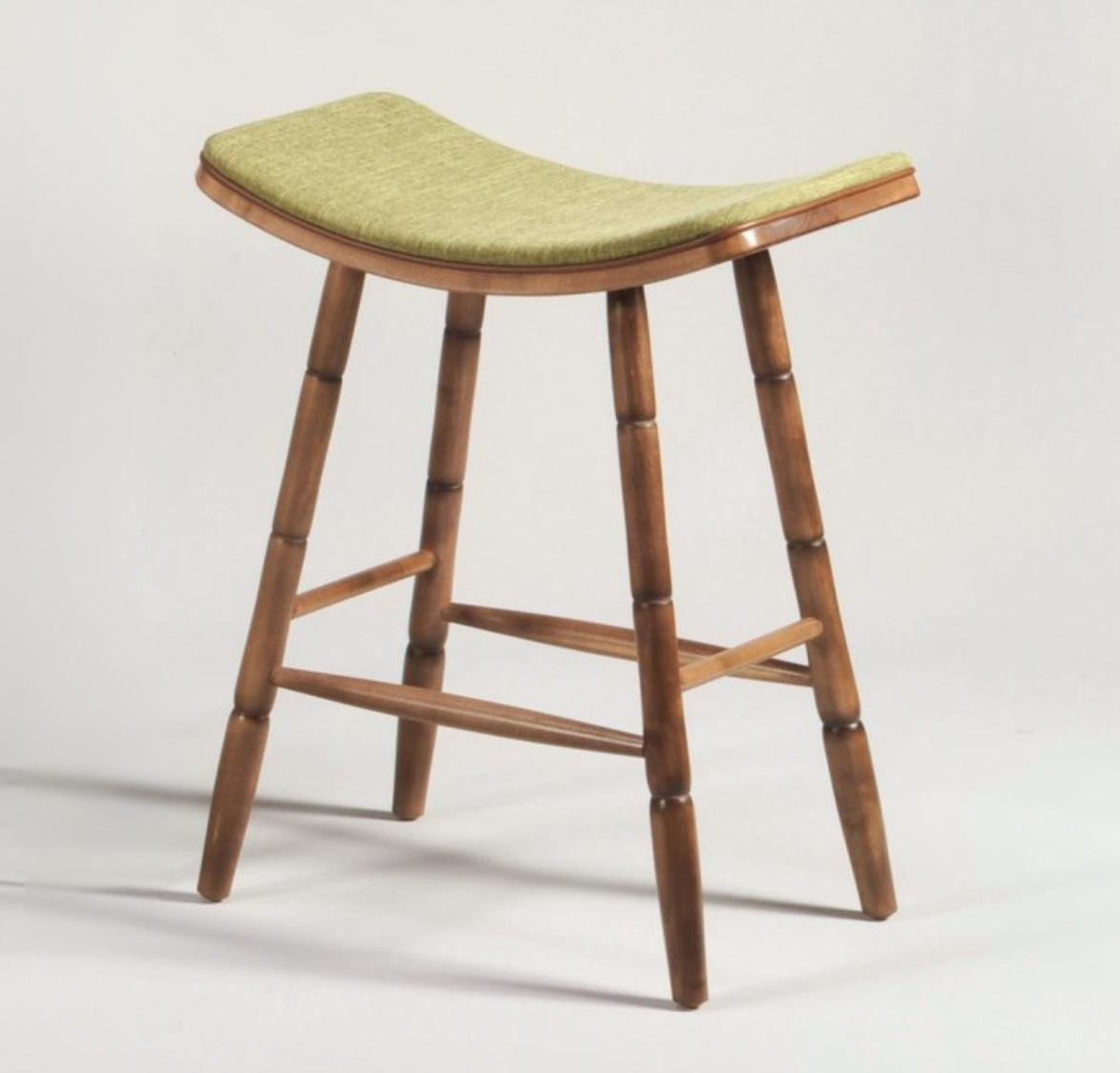 Wooden stool with a green cushioned seat on a light gray background