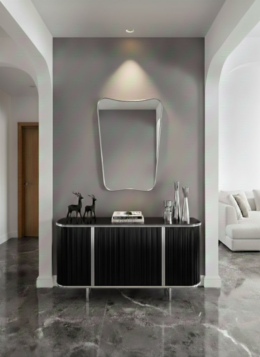 Silver asymmetrical wall mirror above black console table.
