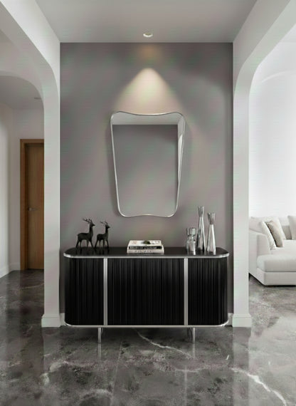 Silver asymmetrical wall mirror above black console table.