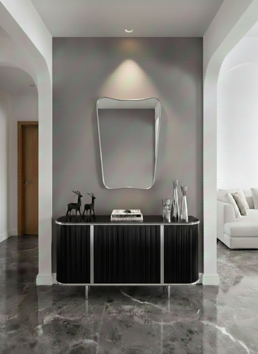 Silver asymmetrical wall mirror above black console table.