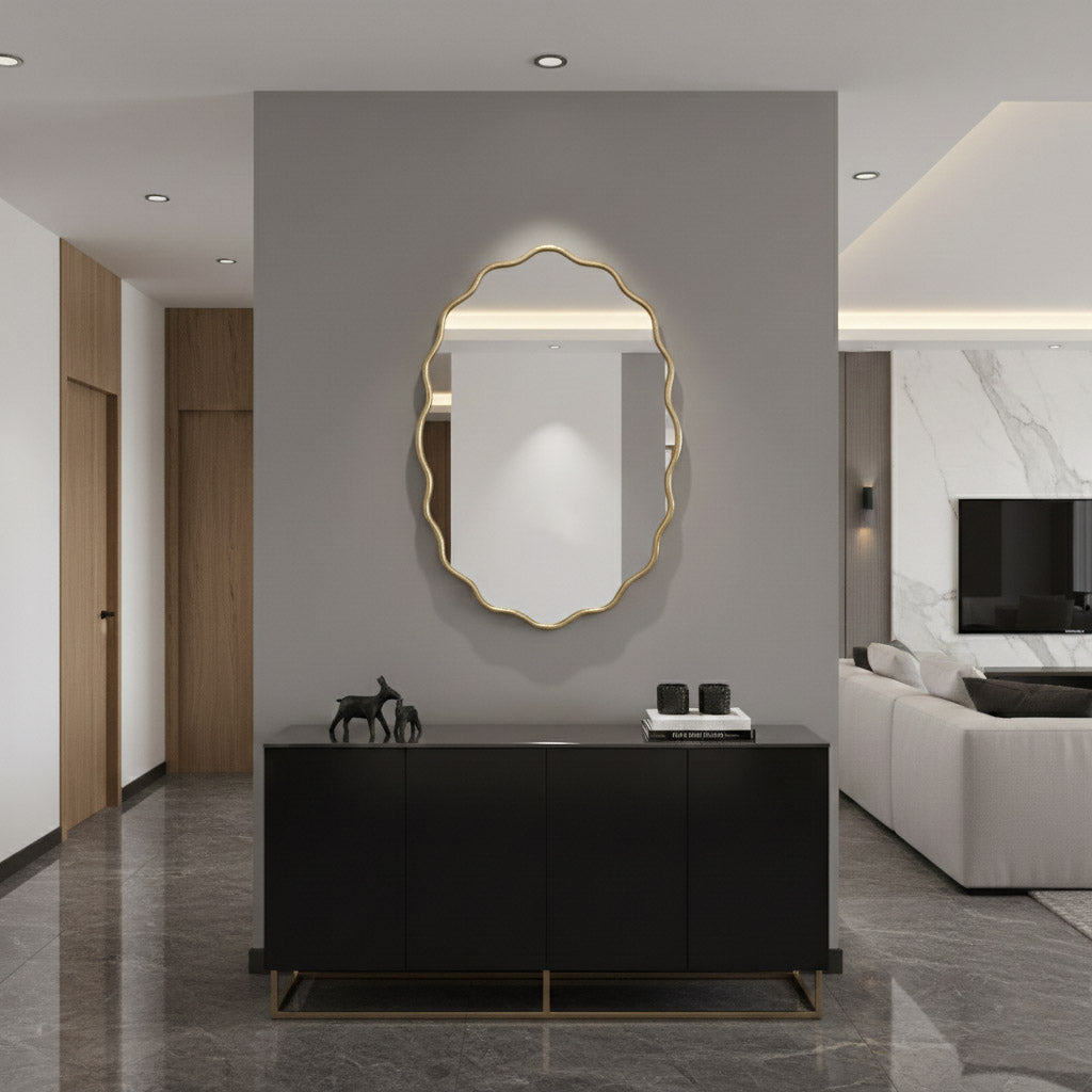 Oval wavy brass mirror above black console in modern hallway.