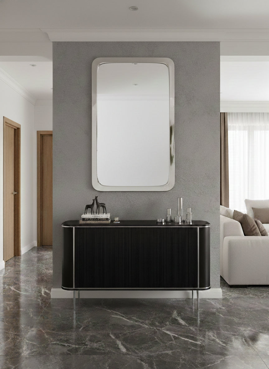 Modern silver rounded rectangle mirror above a black ribbed console table.
