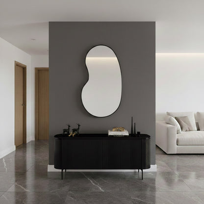 Modern black kidney mirror above black console.