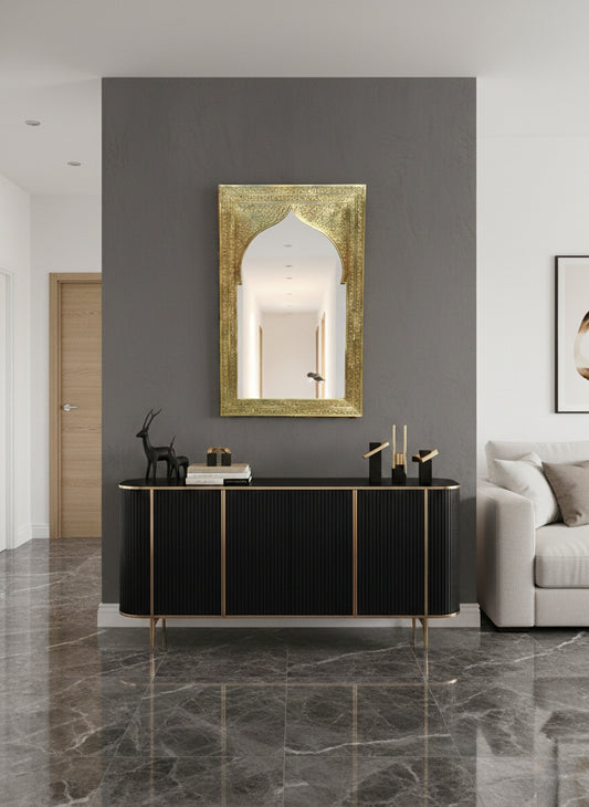 Carved arch brass mirror above a modern console table