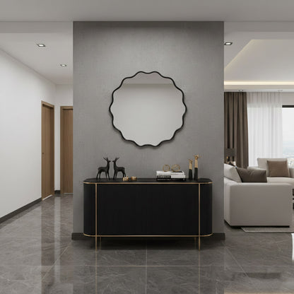 Round wavy black wall mirror above black console in contemporary hallway.