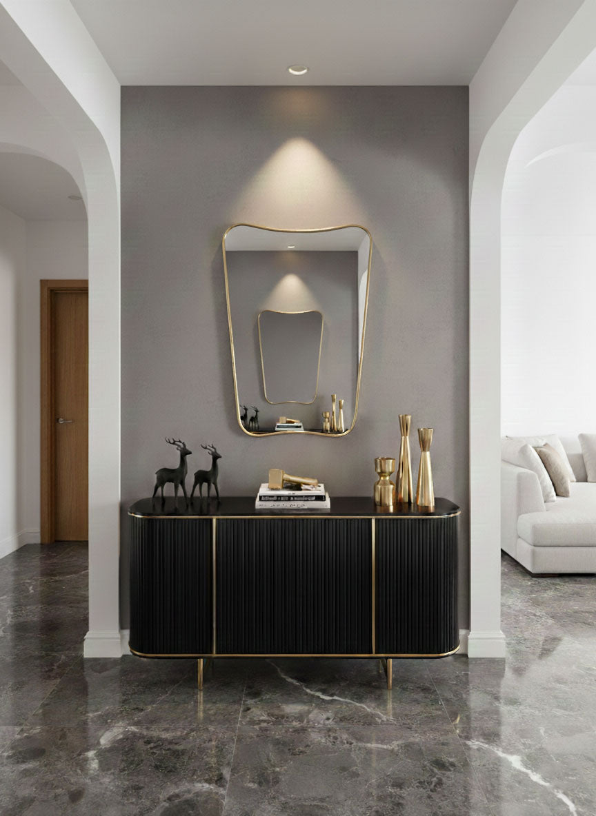 Butterfly brass mirror above black console in entryway
