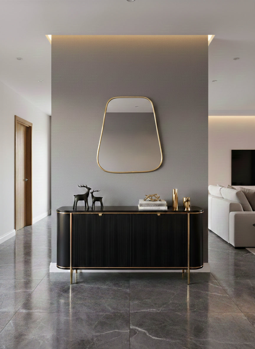 Triangle brass mirror above black console in modern entryway