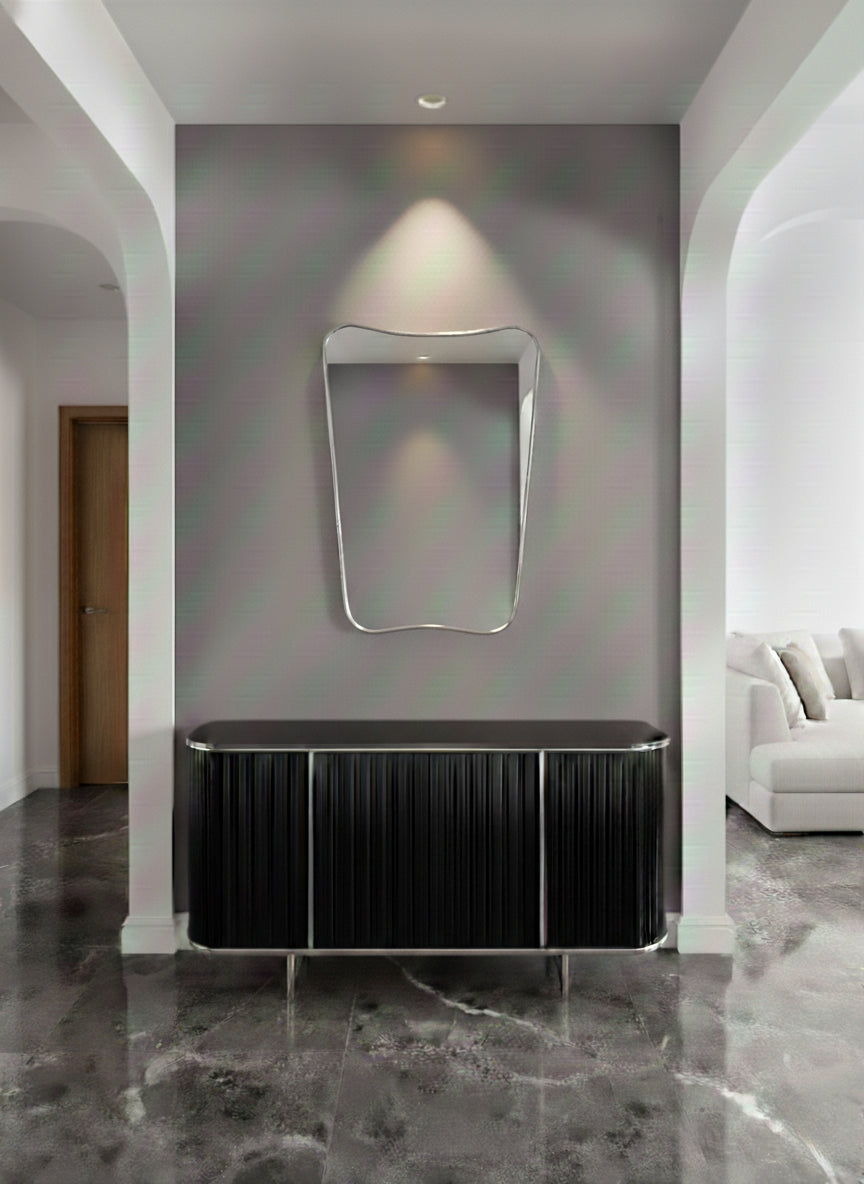 Silver brass mirror mounted above black console in modern entryway.