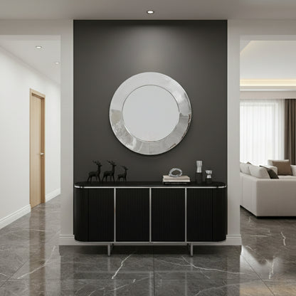 Round silver brass mirror mounted above black console in modern entryway.