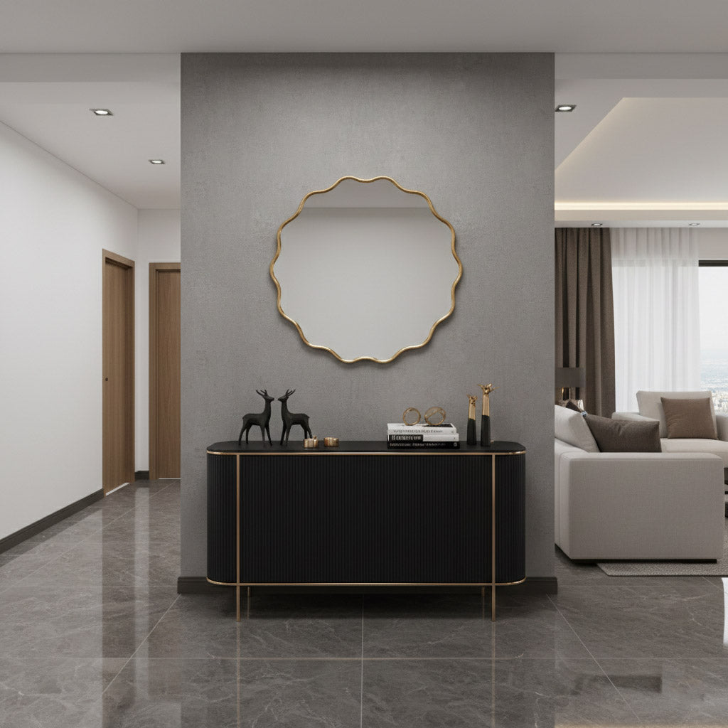 Round wavy brass wall mirror above black console in contemporary hallway.