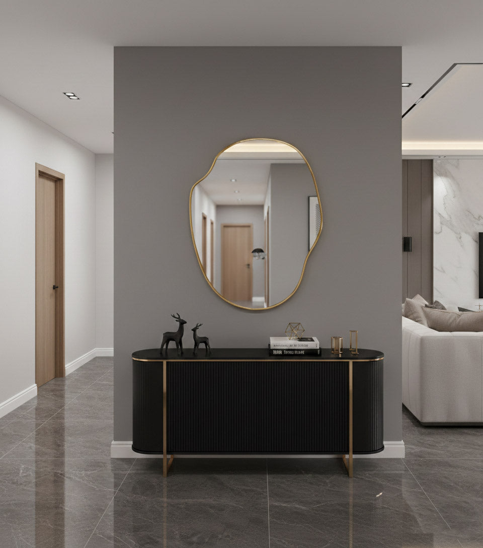 River stone brass mirror above black console in modern hallway.