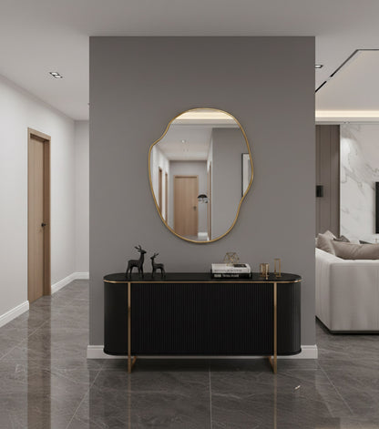 River stone brass mirror above black console in modern hallway.
