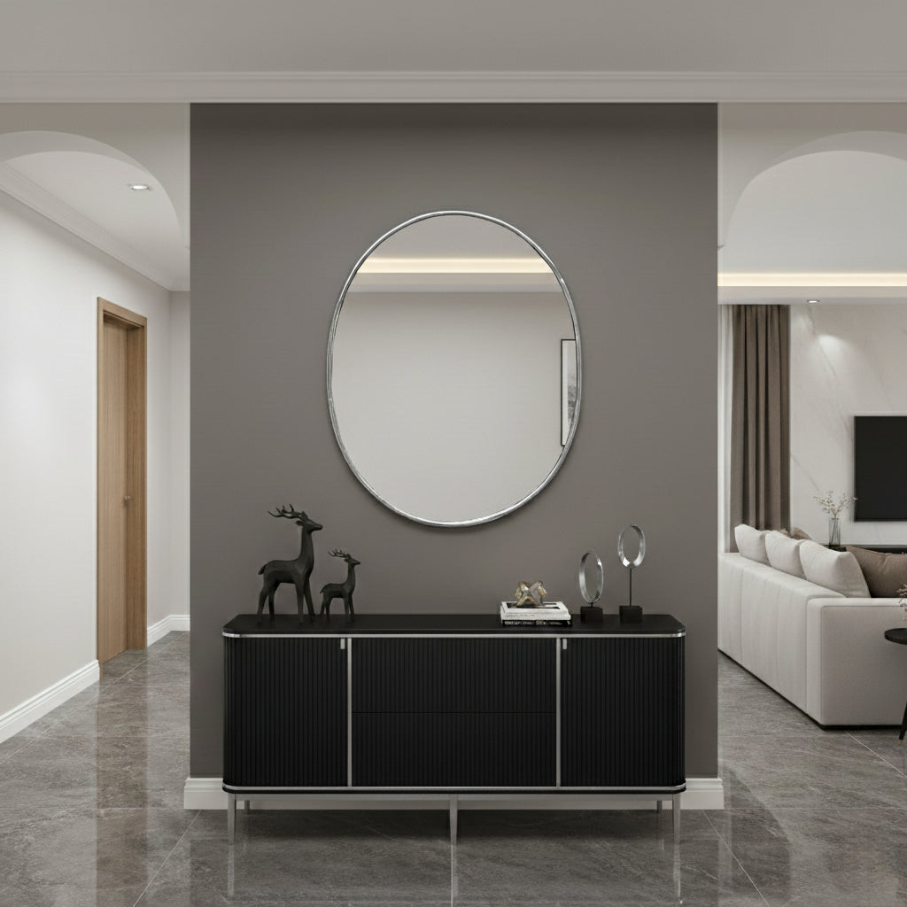 Oval wall mirror above black console in a modern hallway.