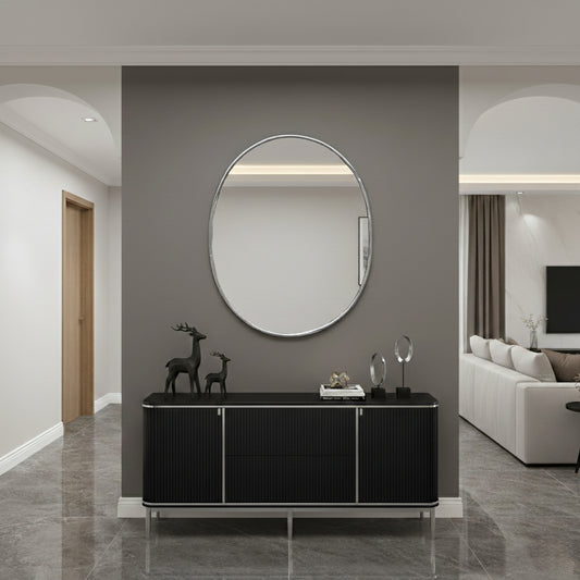 Oval wall mirror above black console in a modern hallway.