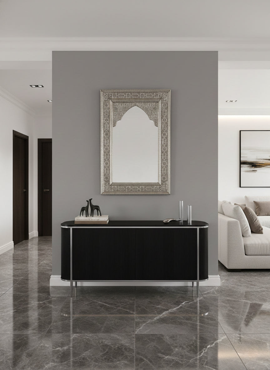 Ornate silver arched mirror above black console table.