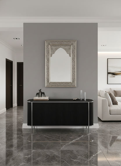 Ornate silver arched mirror above black console table.