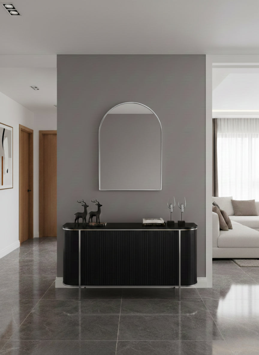 Silver arch wall mirror above black console in modern hallway.