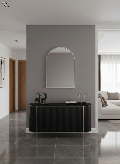 Silver arch wall mirror above black console in modern hallway.