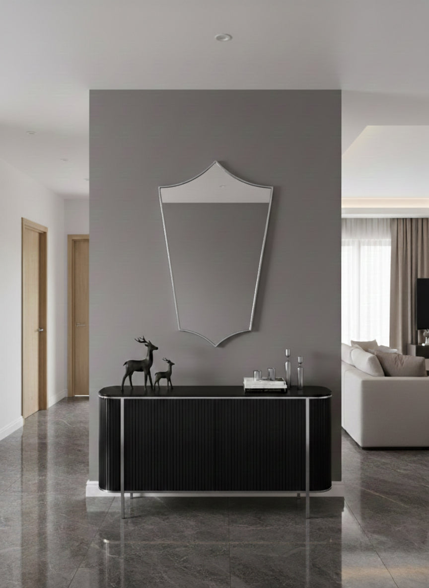 Contemporary shield mirror above black console in a minimalist hallway.