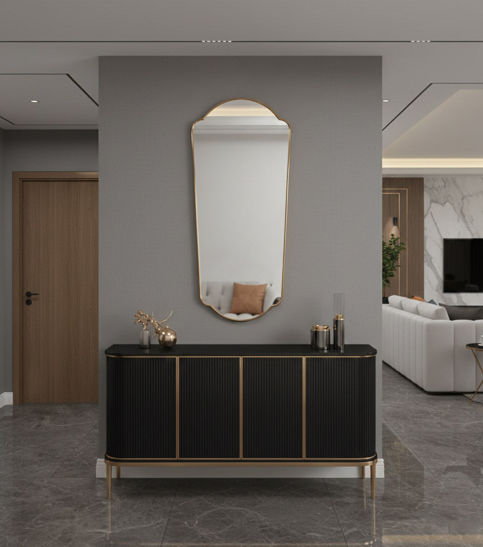 Full length brass mirror above black console in modern entryway.
