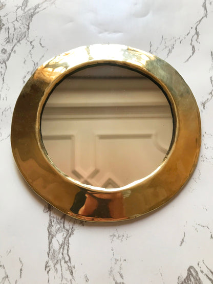 a round mirror on a marble counter top