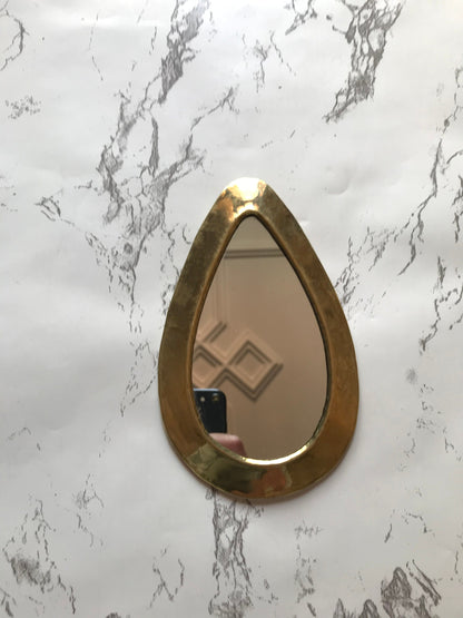 a mirror with a gold frame on a marble wall