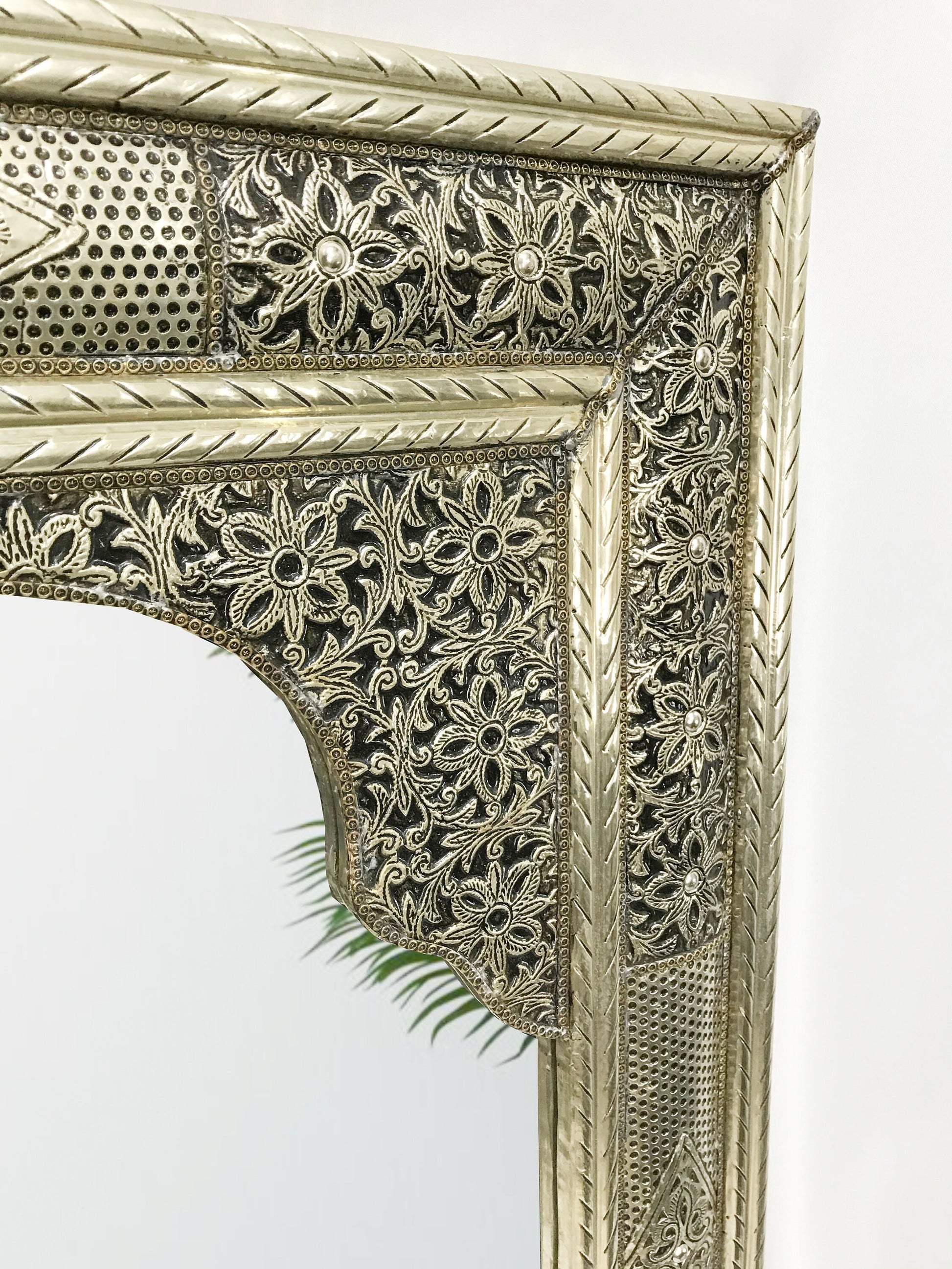 an ornate gold mirror with a plant growing out of it