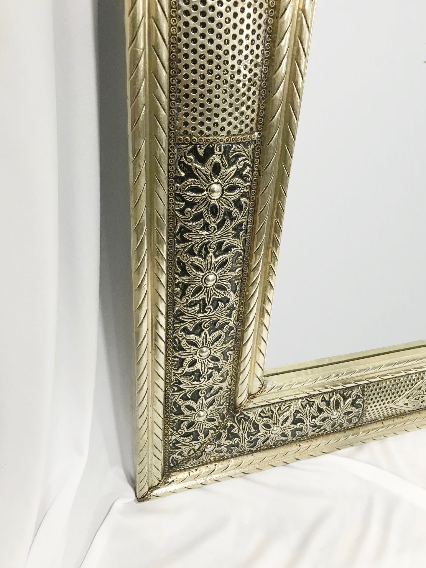 a gold framed mirror sitting on top of a white sheet