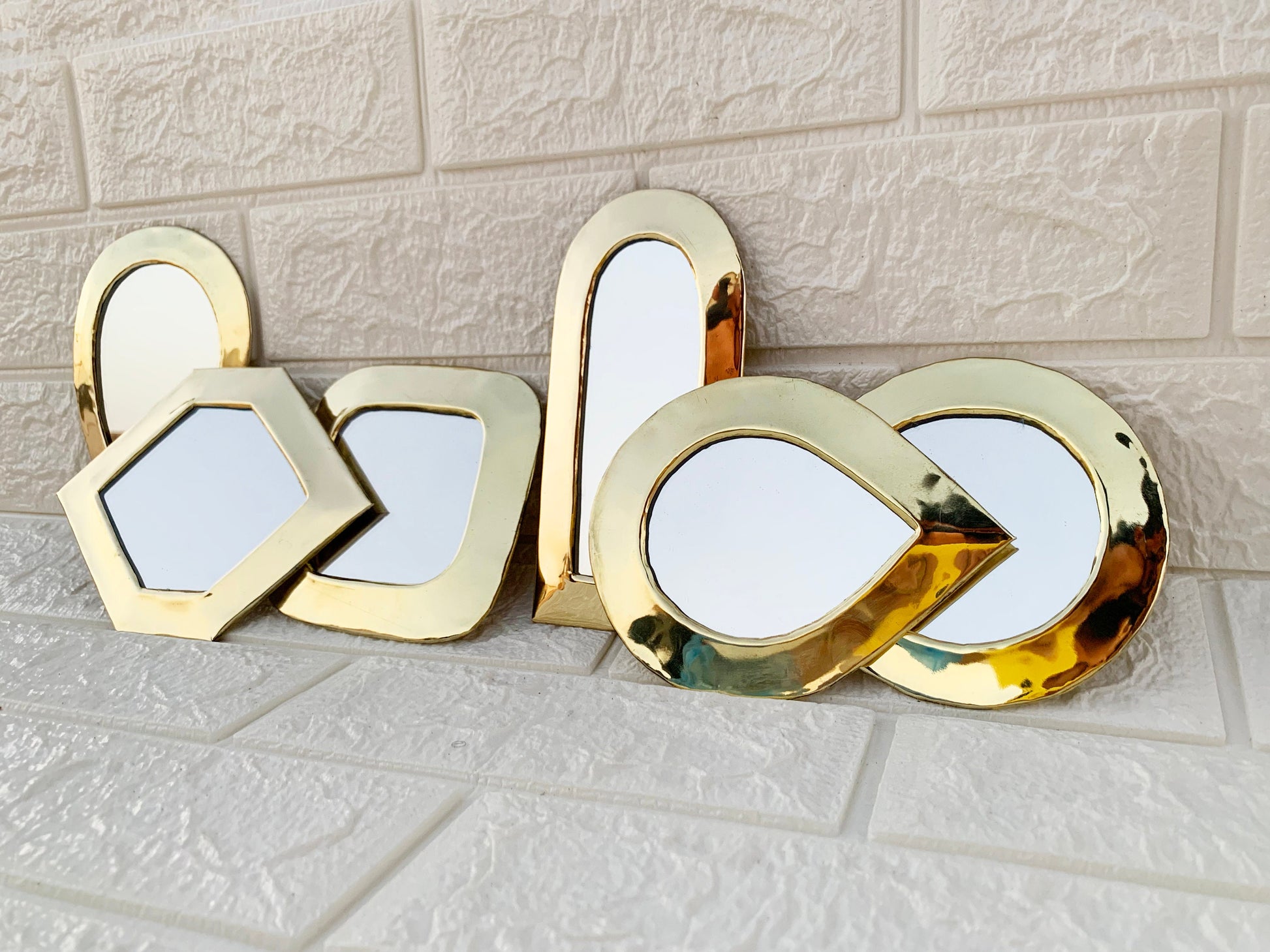 a set of three mirrors sitting on top of a tiled floor