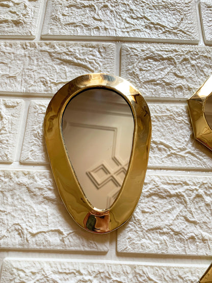 a gold mirror mounted to a white brick wall