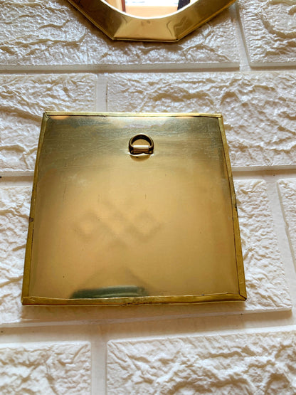 a gold square shaped object on a white brick wall