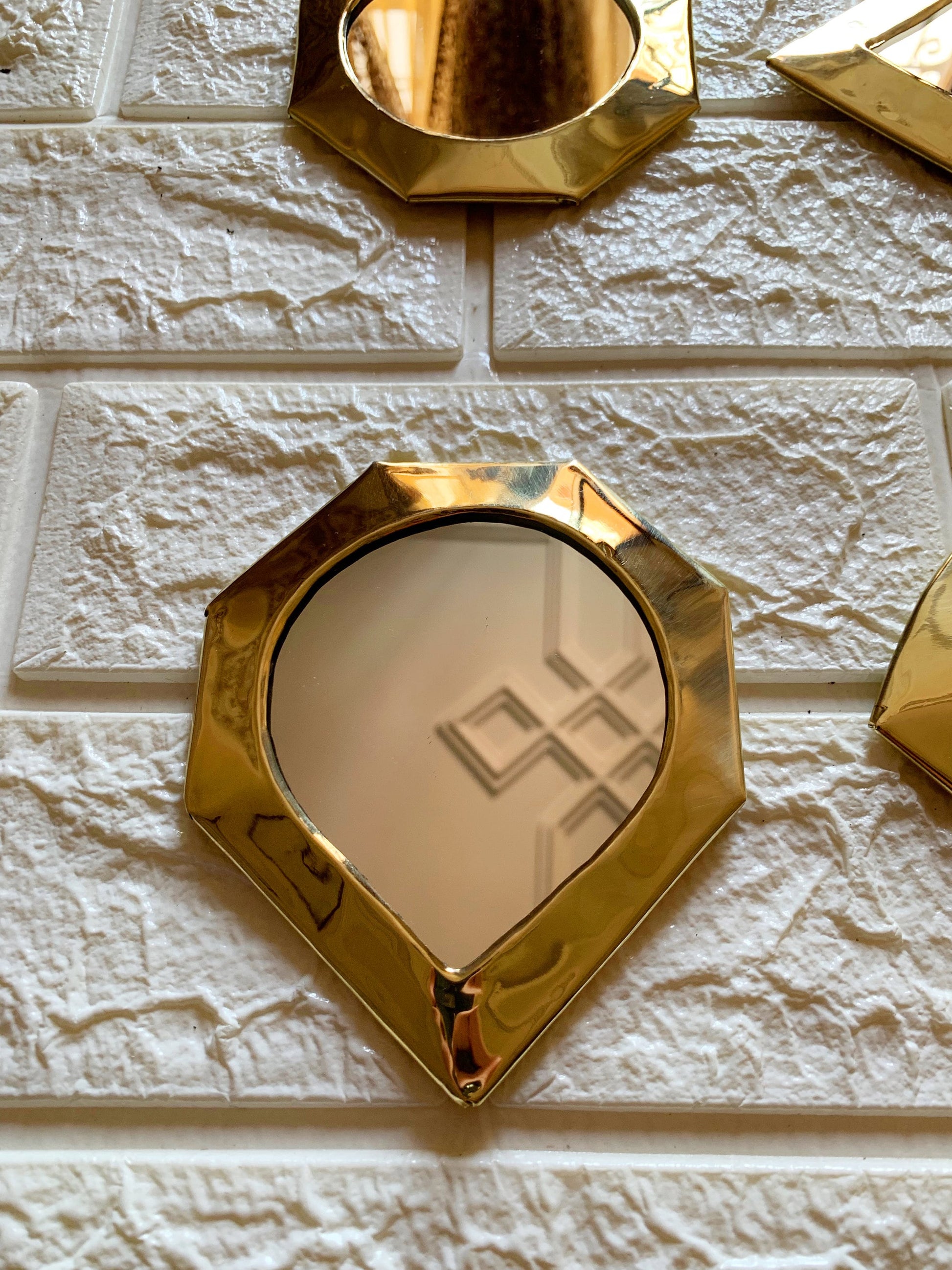 a white brick wall with gold mirrors and a mirror on it