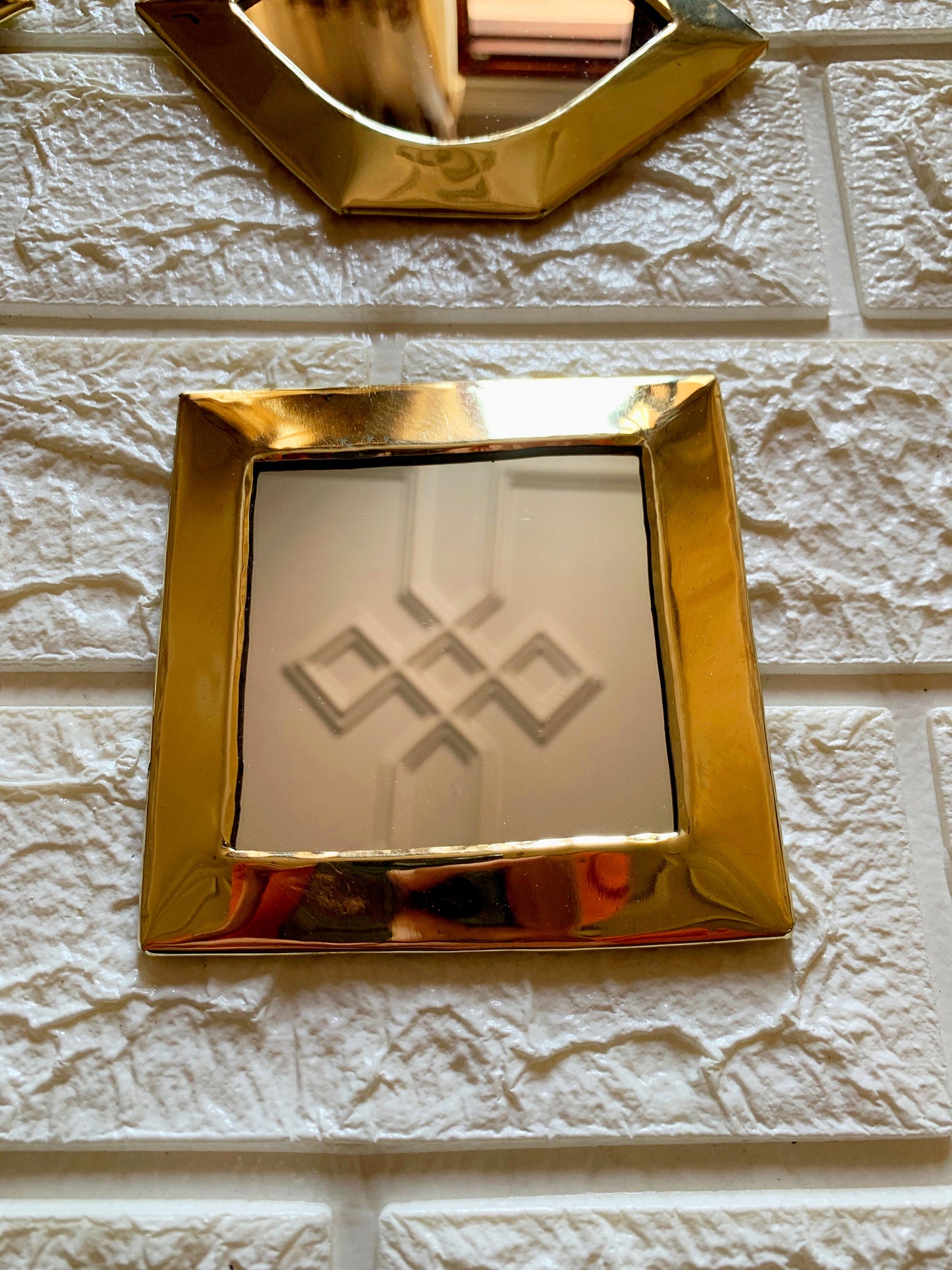 a gold frame on a white brick wall