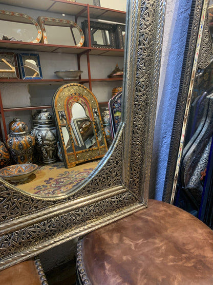 a mirror sitting on top of a table next to a stool