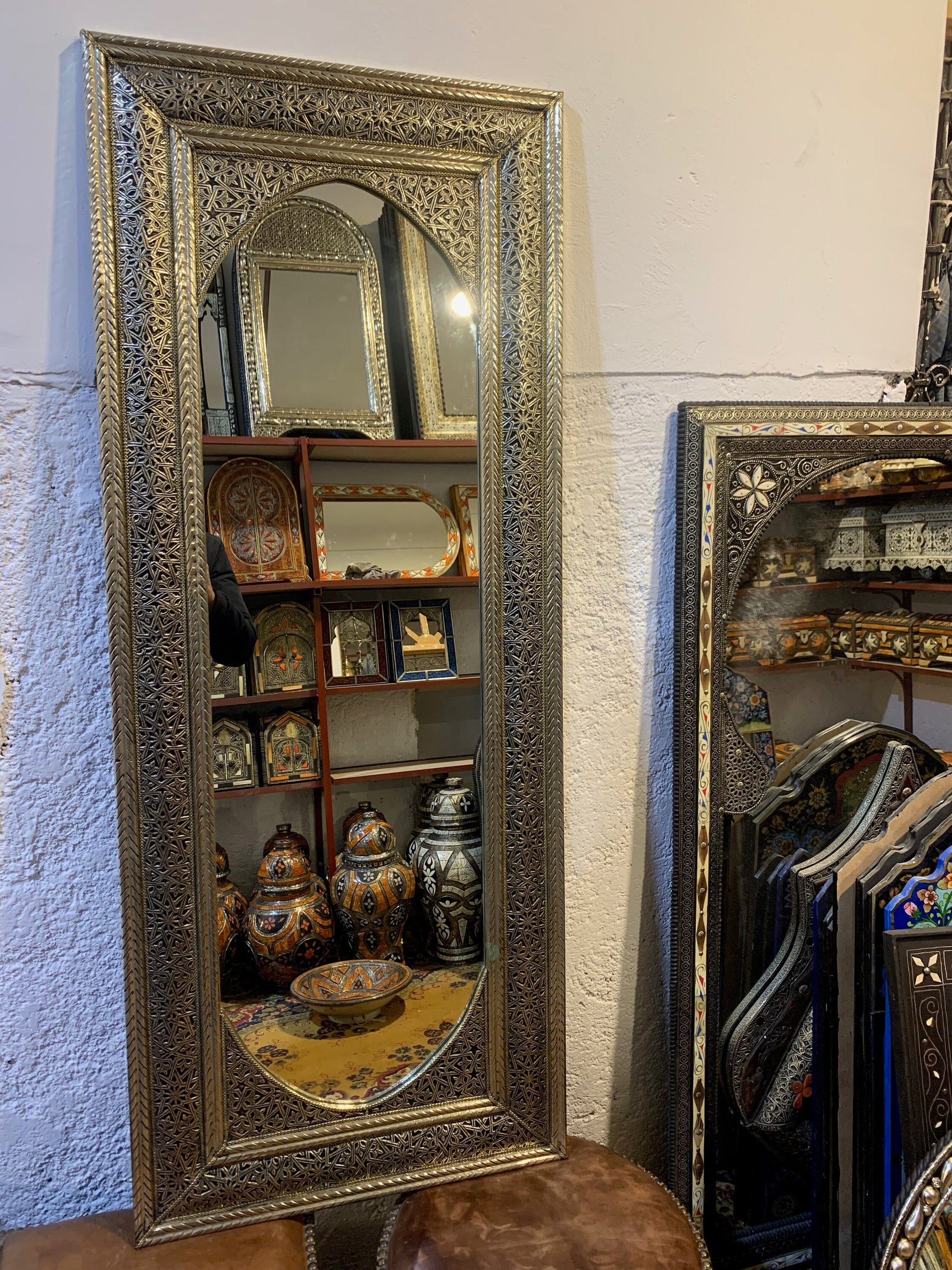 a full length mirror sitting on top of a table next to a chair