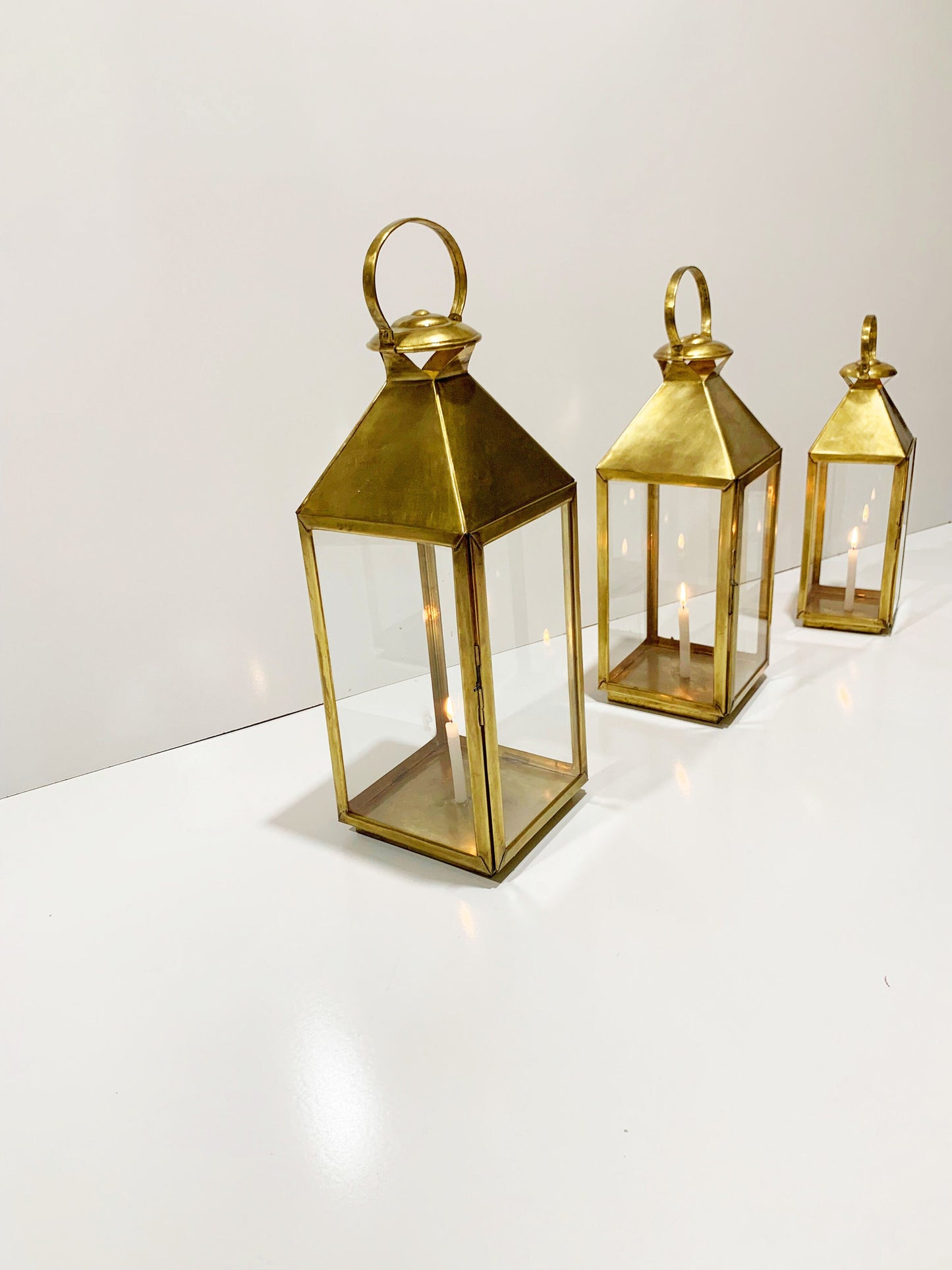 three gold colored lanterns sitting on top of a white table