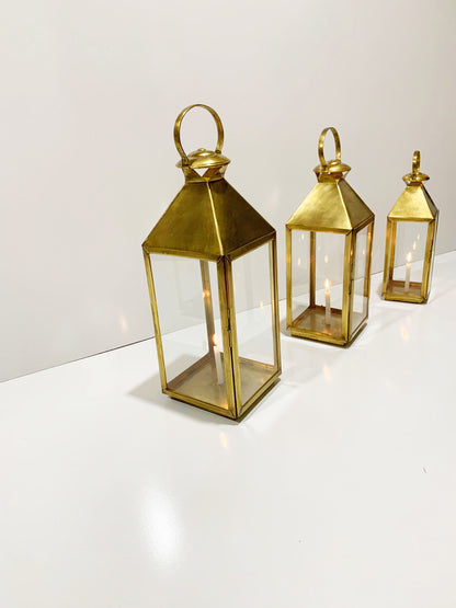 three gold colored lanterns sitting on top of a white table