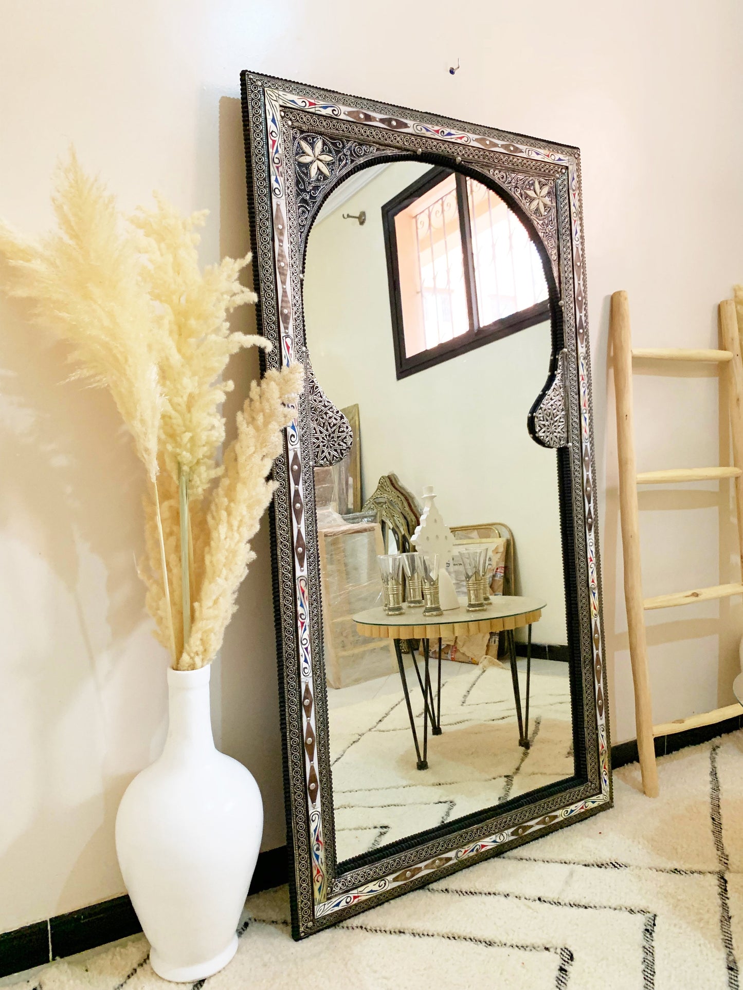 a mirror sitting on top of a floor next to a vase