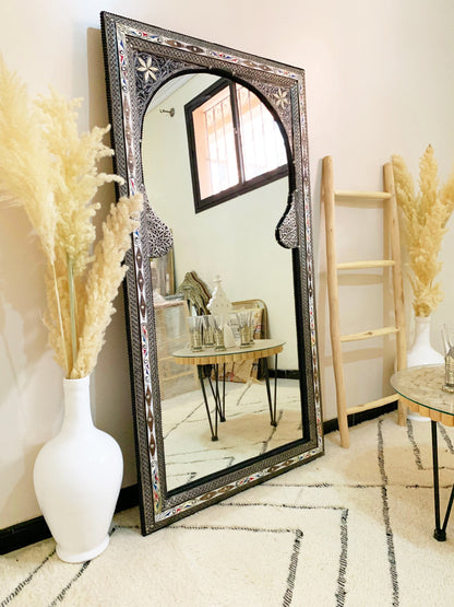 a full length mirror sitting on top of a floor next to a table