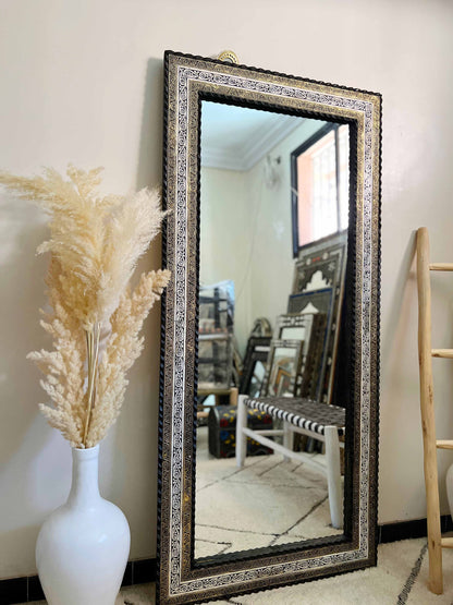 a mirror sitting next to a vase with a plant in it