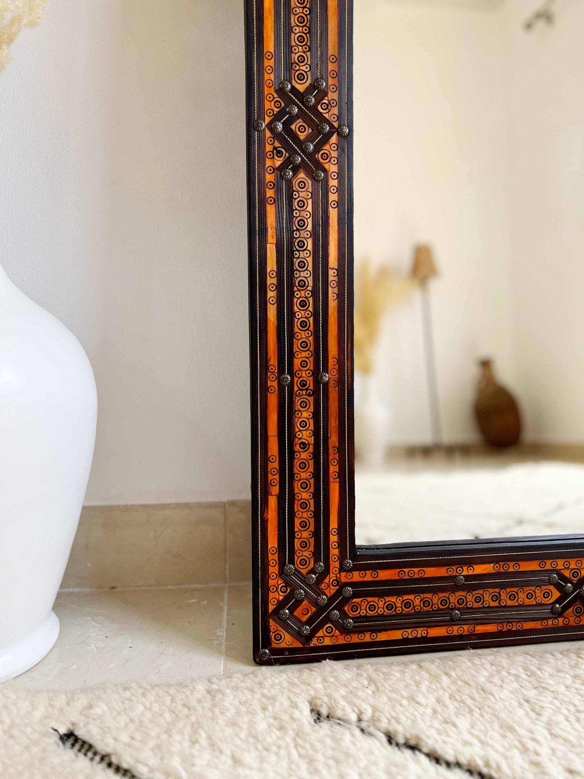 a mirror sitting on top of a table next to a vase