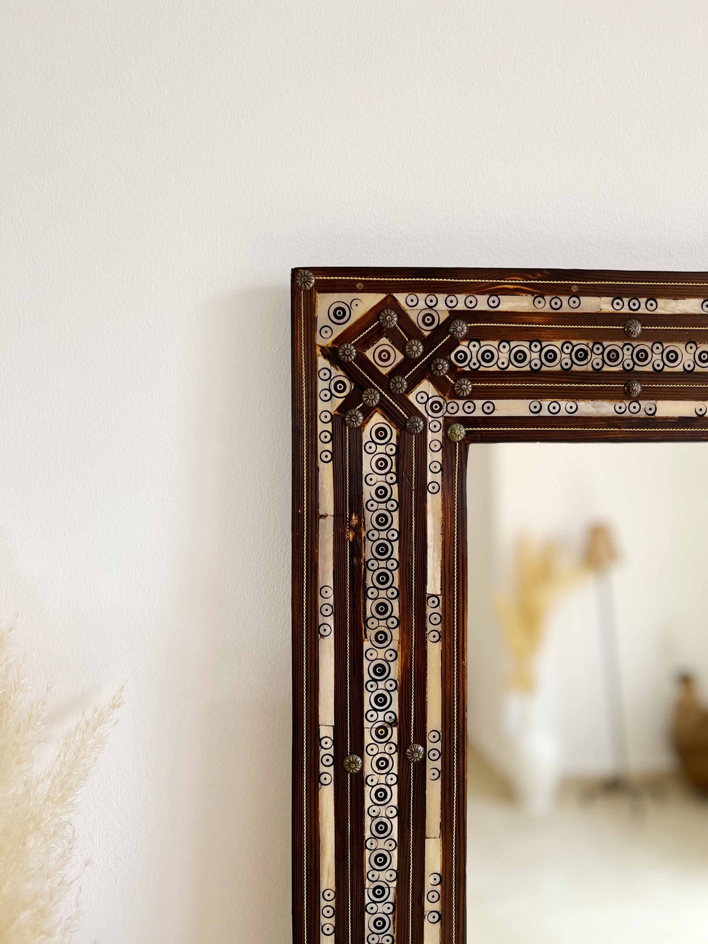 a mirror sitting on top of a table next to a vase