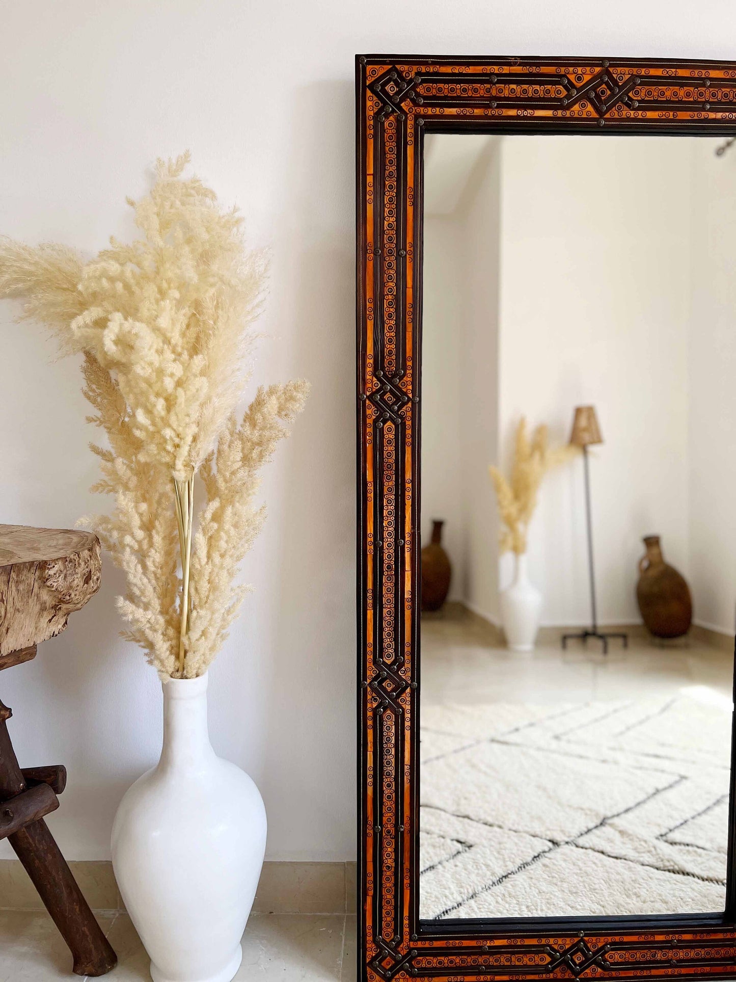 a large mirror sitting next to a white vase