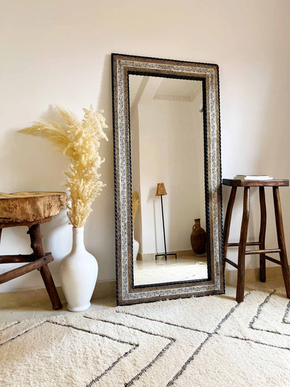 a white vase sitting next to a tall mirror